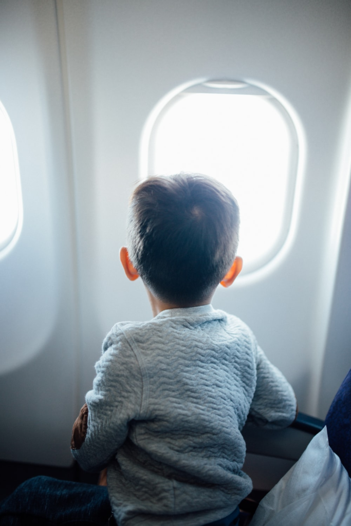 a boy looking outside of the plane’s window