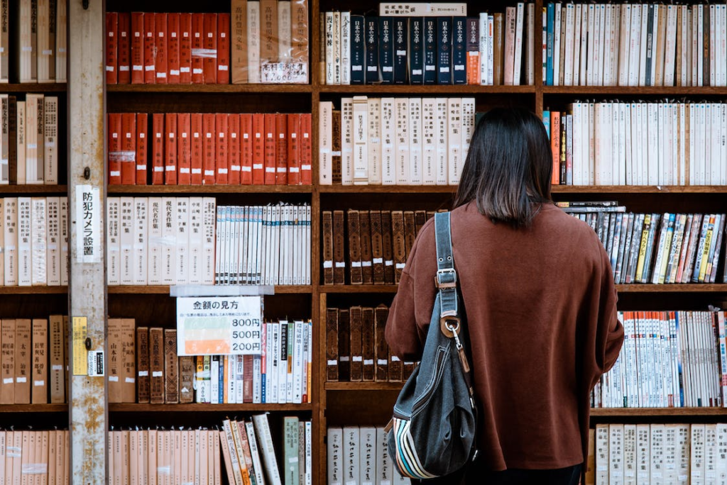 A student standing in front of a bookshelf