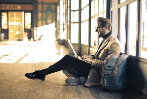 a person sitting on the floor while working on their laptop