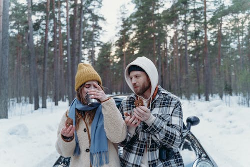 Two people having a snack while traveling in winter