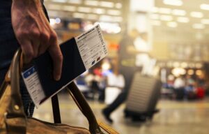 a person carrying a passport, ticket, and bag