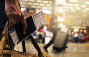 A person at the airport carrying a bag, boarding pass, and passport