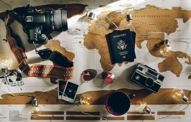 A photo showing a camera and passport resting on top of a world map.