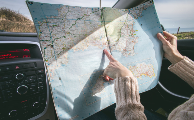 A photo showing a person in a sweater holding a map.