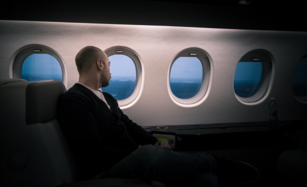 A photo showing a person looking out the window of a plane.