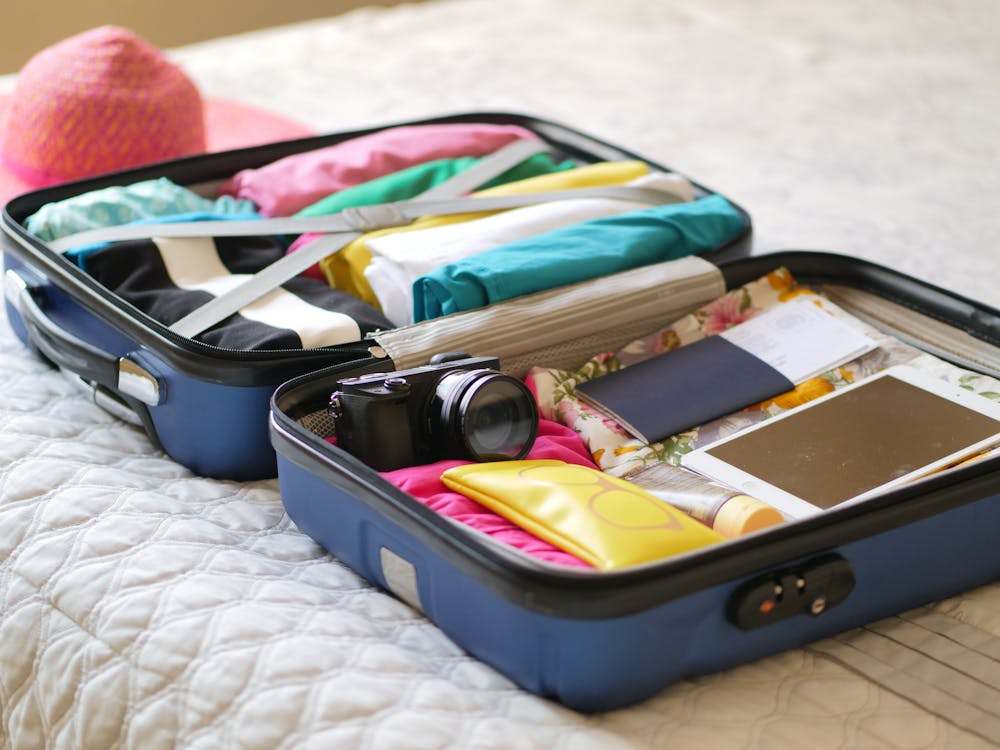 A luggage with neatly organized clothing, a camera, and other traveling essentials