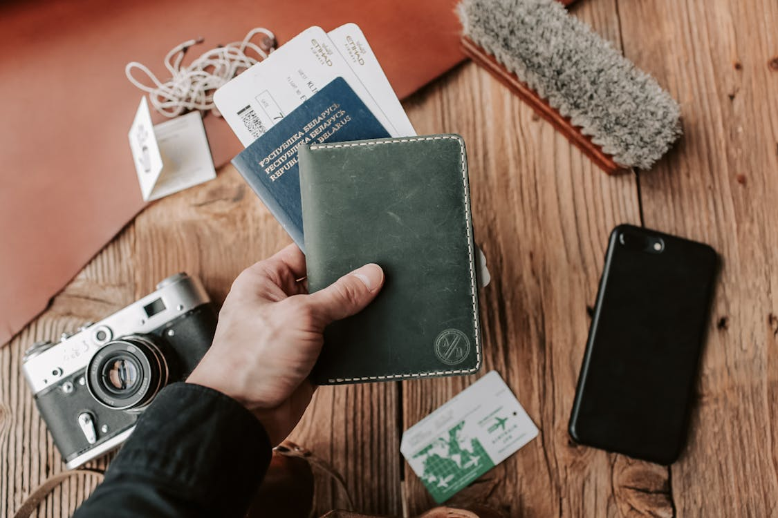 A person holding an expedited passport with other travel essentials