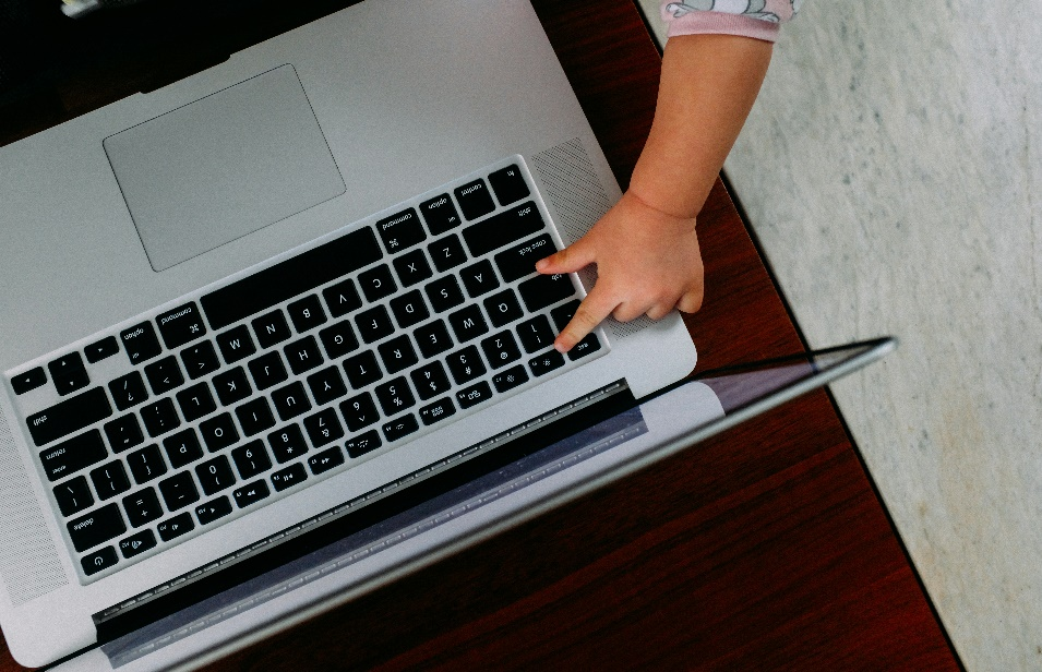 A baby's hand pointing on a laptop keyboard.