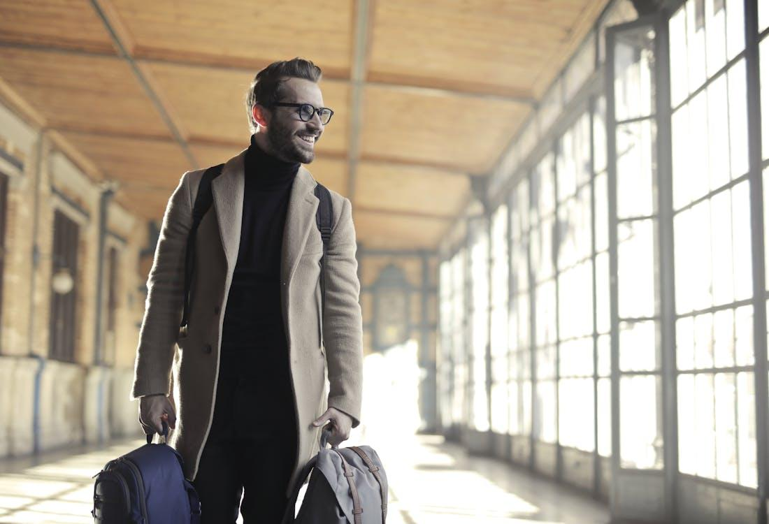 A man in a brown robe smiling while carrying a bag, ideal for business travel with an expedited passport.