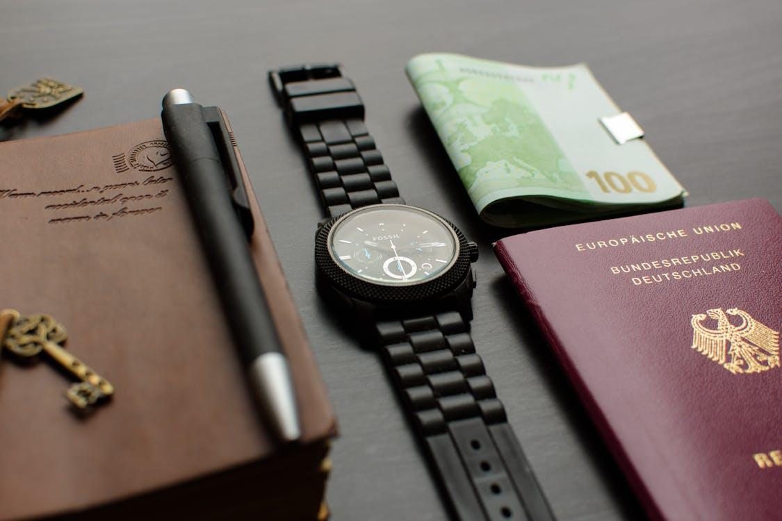 A round black chronograph watch placed near a German passport